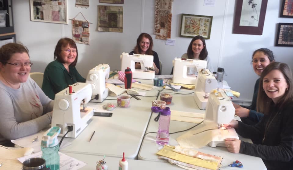 Image shows a group of people enjoying a sewing class