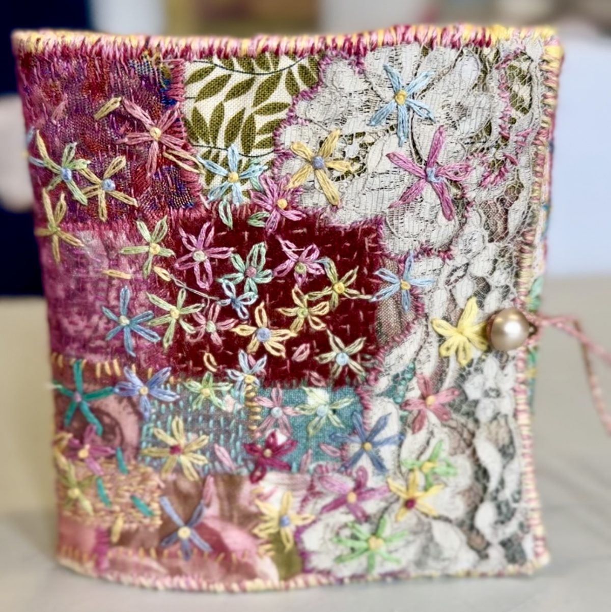 Slow-Stitched Needlebook - image of a hand-embroidered needlebook made with small fabric scraps & vintage lace. Includes boro stitching, running stitch, chain stitches and lazy-daisy stitch